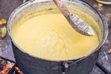 Polenta food prepared in a large pot with fire and woods