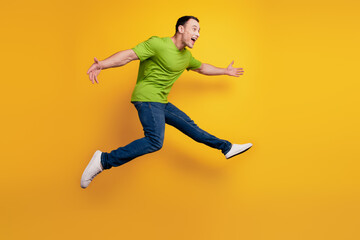 Portrait of sportive energetic guy jump hurry run on yellow wall