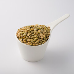 white dish cup full of green lentil. isolated on white