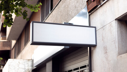 White commercial signboard blank space for mockup for logo design on a store wall in the street