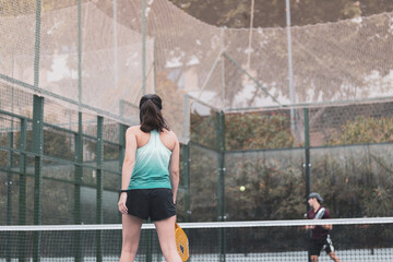 a couple of a boy and a girl playing paddle tennis outdoors.