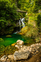 Fototapeta na wymiar Vintgar Gorge in Slovenia. Wooden Bridge and Path Over Waterfall
