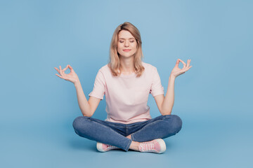 Portrait of peaceful dreamy inspired girl sit floor meditate close eyes on blue background