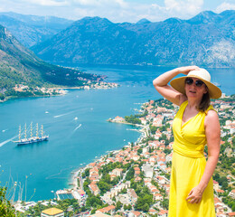 Elegant woman in sunglasses and straw hat posing high above the city