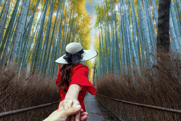 A woman tourist is hand to hand sightseeing and traveling at Arashiyama Bamboo Forest in Kyoto,...