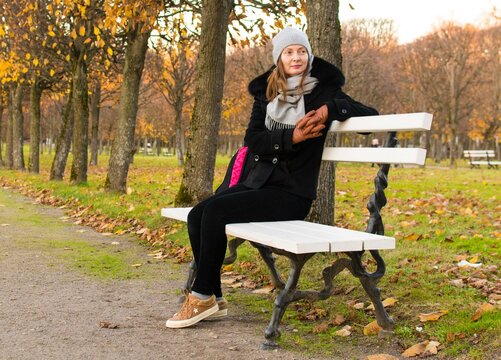 Russia, the village of Arkhangelskoe. October 7, 2020. Portrait of a beautiful woman in autumn in the park in nature, sitting on a bench.