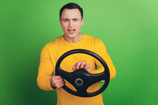 Portrait of offended driver guy hold steering wheel grimace on green background