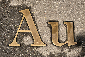 Worn brass Aurum or gold sign in stone or asphalt on the road. Selective focus