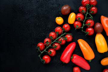 Tomatoes, cherry tomatoes and peppers on black background. Healthy eating and vegetarian food, cooking concept. Low key, selective focus. Top view, flat lay, copy space