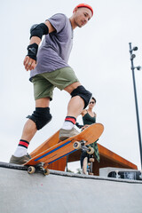 Fototapeta na wymiar Indecisive mature skater in a watch cap standing on the skateboard edge
