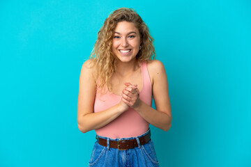 Young blonde woman isolated on blue background laughing