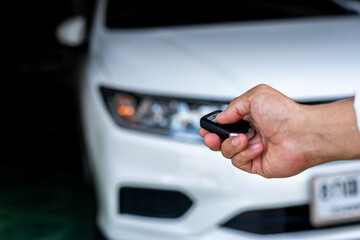 Hand of a man holding and push remote control of white car, technology transportation safety concept