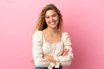 Young blonde woman isolated on pink background keeping the arms crossed in frontal position