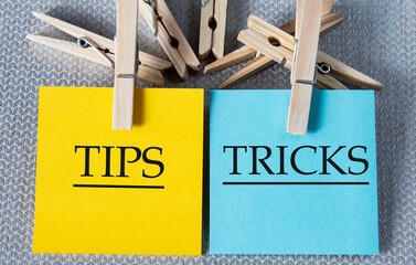 TIPS TRICKS - words on multicolored writing paper on gray background with clothespins