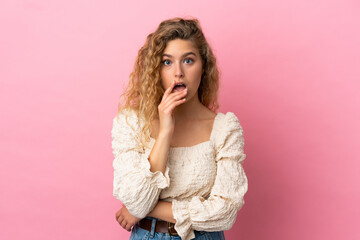 Young blonde woman isolated on pink background surprised and shocked while looking right