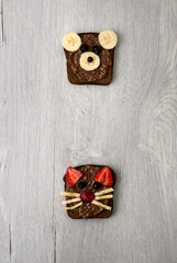 Vegetarian whole grain toasts with black currant, strawberry, banana and chocolate veggie paste, funny sandwich for children. Healthy kid food concept. Close-up, selective focus. Top view, flat lay