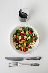 Healthy veggie salad with avocado, arugula, spinach, strawberries, cashews and seeds- low carbohydrate, low calorie diet. Healthy eating, nutrition and diet concept. Top view, flat lay