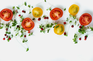 Close up composition of cutted red and yellow cherry tomatoes with microgreens and pink pepper on light background