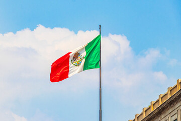 Mexican flag green white red with blue sky Mexico City.