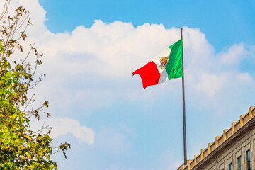 Mexican flag green white red with blue sky Mexico City.