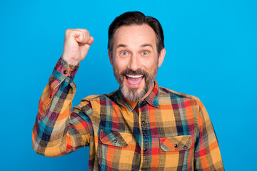 Naklejka premium Photo of astonished brunet hairdo mature man hand fist wear plaid shirt isolated on blue color background