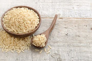 closeup of uncooked long brown rice on the wooden table