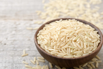 closeup of uncooked long brown rice on the wooden table