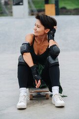 Happy woman skater with short hair resting on her board, enjoying herself.