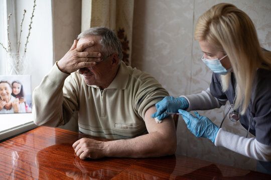 Doctor preparing vaccination shot to elderly patient by holding syringe at home - concept of home health check to seniors during coronavirus covid-19 pandemic