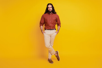 Fototapeta premium Portrait of confident masculine guy hands pockets posing on yellow background