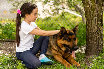 beautiful little girl with a german shepherd playing on the lawn at the day time