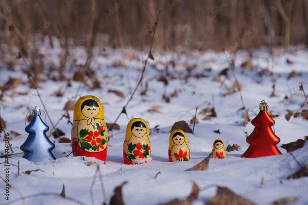 Wall mural A row of nesting dolls and toy Christmas trees in the winter forest.