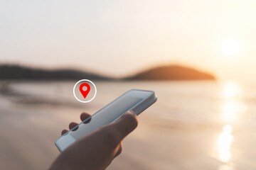 Woman hand using smart phone with navigator location point at tropical sunset beach abstract...