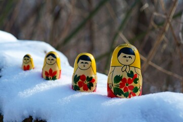 Figurines of nesting dolls in the winter forest.