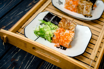 Several sushi on a white plate standing on a brown wooden background
