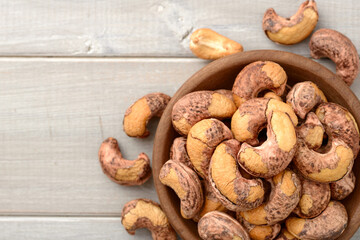 roasted cashew nuts in the wooden bowl on the table, top view
