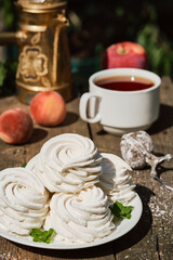 Dessert zephyr (marshmallow) on a white plate, on an old wooden table, afternoon tea in the garden. Airy Russian dessert close up, selective focus.
