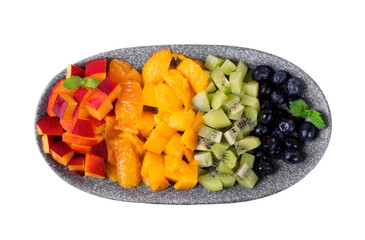 Assorted chopped fruits and berries in rows reminding rainbow colors on the plate isolated on white. Nectarine, orange, mango, kiwi and blueberry