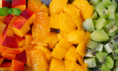 Assorted chopped fruits in rows. Nectarine, orange, mango and kiwi. Full frame. Food background