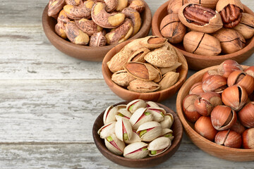 multiple nuts in the wooden bowl, on the wooden board