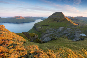 The top of the mountain of Faroe islands. A view of high peaks of mountains on a sunny day. Ocean view. 
Beautiful panoramic view. Northern Europe. Travel concept