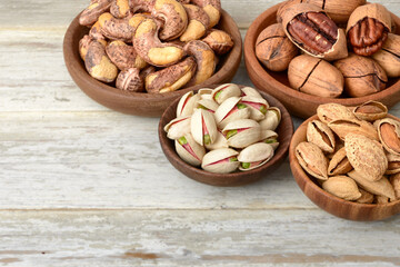 multiple nuts in the wooden bowl, on the wooden board