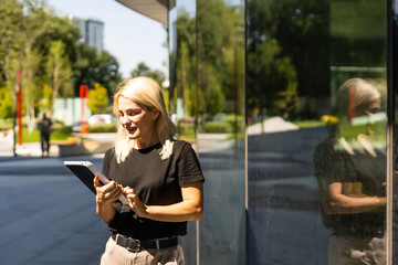 Fototapeta premium Portrait of a successful woman using digital tablet during quick break in front a corporate building.