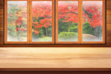 Blank Wooden table top with wood window and autumn garden display for product concept