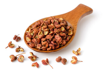 dried Szechuan peppercorns in the wooden spoon, isolated on the white background