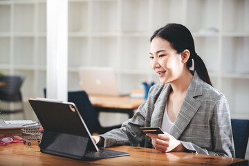 girl holding a credit card and using a laptop Business woman working from home . online shopping, ecommerce, internet banking, spend money, work from home concept.