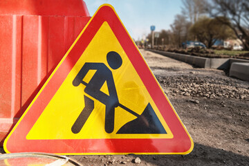 The warning sign for road repair work lies on the roadway