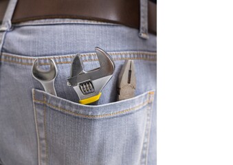 Close up view of multiple tools in the jeans pocket of repairman
