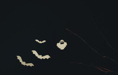 Halloween decoration, ghosts and paper bats, tree branches on a black background. Backdrop for holiday and party, copy space