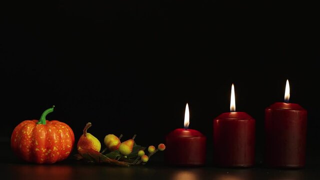 Burning candles and pumpkin with autumn fruits, halloween horror story. Isolated image on black background, copy space. Video, footage or background for splash screen, credits, cutouts, intro. UHD 4K